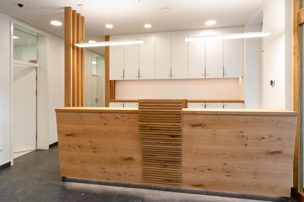 Modernes Design des Empfangtresens einer Praxis mit hellem Holz